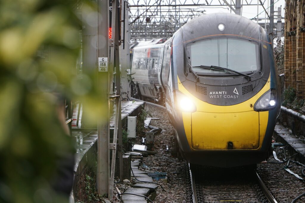 A yellow and black train traveling down train tracks